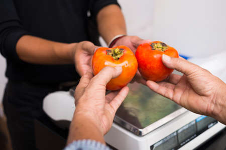 Cropped image of a buyer giving to the seller the vegetables on the foreground の写真素材