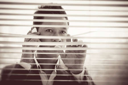 Copy-spaced image of a businessman having serious telephone call through the shutter on the foreground の写真素材