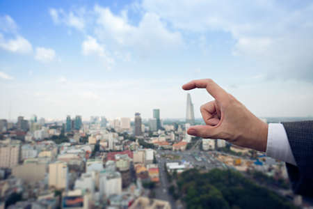 Cropped image of a businessman making a hand frame of a modern building on the foregroundの写真素材