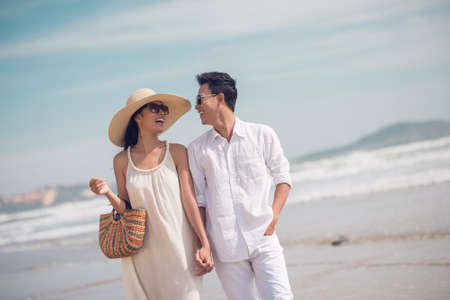 Close up image of a young glamorous couple walking together on the beach in the summertime の写真素材