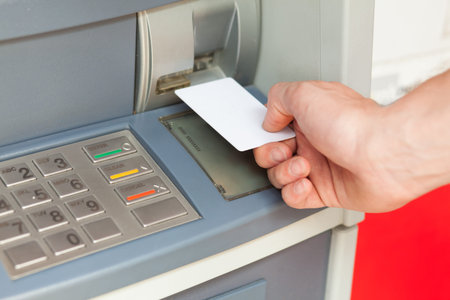 Close up image of a human hand inserting a credit card in the ATM
