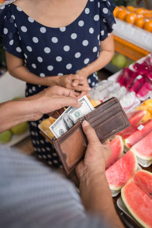 Vertical image of a man holding money for fruits paying on the foreground の写真素材