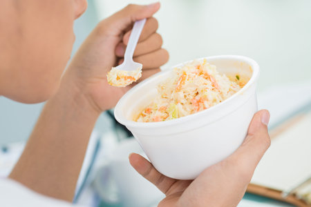 Close-shot of a white collar worker having a snack in office environmentの写真素材