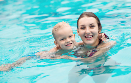 Adorable mom and kid keeping fit and healthy in waterの写真素材