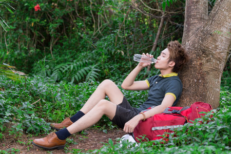 Lying tired tourist drinking water in the forest