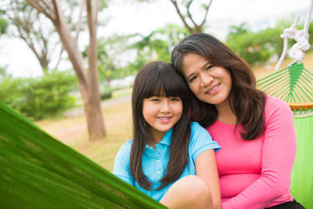 Portrait of a smiling mother and a daughter embracing and looking at cameraの写真素材