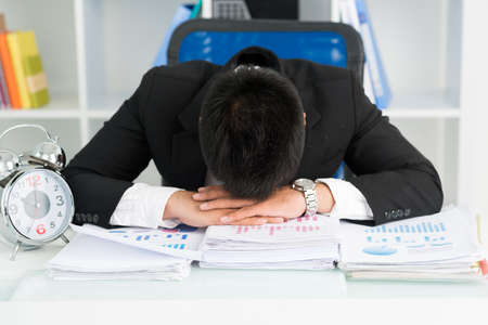Tired businessman putting head on the tableの写真素材