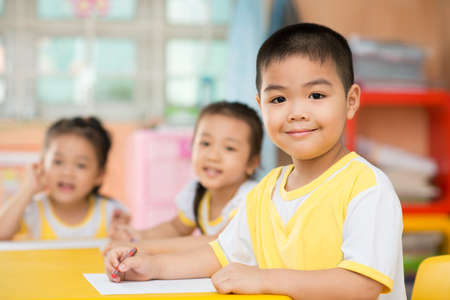 Two girls and a boy sitting behind the deskの写真素材