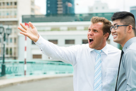 Businessman with a what-the-heck look on his face observing the downtown together with his colleagueの写真素材