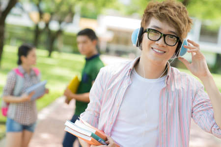 Portrait of a teenage boy listening to the music and looking at camera outsideの写真素材