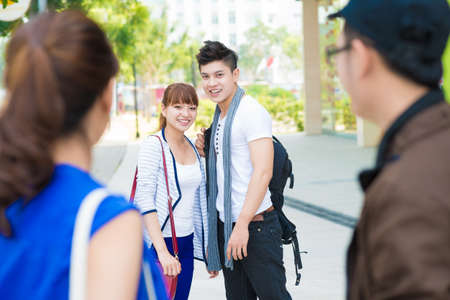 Happy asian friends outdoors smiling and looking at cameraの写真素材