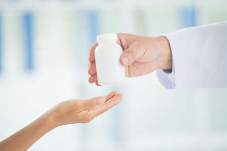 Close-up a doctor?s hands giving a container with treatment to the patientの写真素材