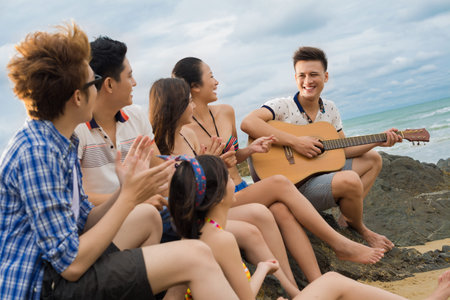 Image of a friend team singing and playing the guitar on the coast 