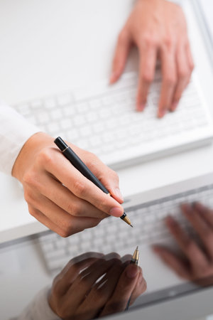 Close-up of hands with a stylus touching a computer screen 