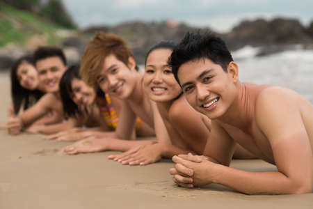 Portrait of a group of friends sun bathing together on the beachの写真素材