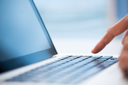Macro image of a finger being about to press a key on a laptop keyboard