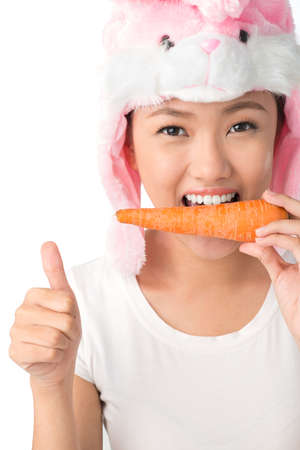 Vertical portrait of cute teenager in bunny hat keeping to a healthy dietの写真素材
