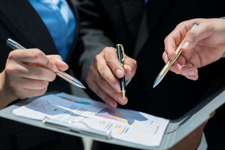 Close-up of human hands holding ballpoints and working with the business diagramの写真素材