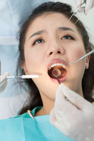 Vertical image of a patient and doctors hands with dental equipment in handsの写真素材