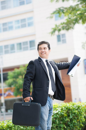 Vertical image of a modern businessman with a handbag standing outsideの写真素材