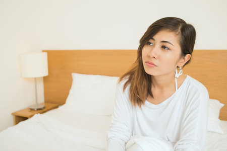 Copy-spaced image of a young woman sitting on the bed just after morning awakening