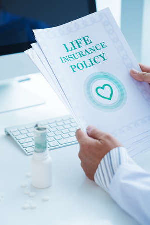 Close-up of human hands holding documents for life insuranceの写真素材
