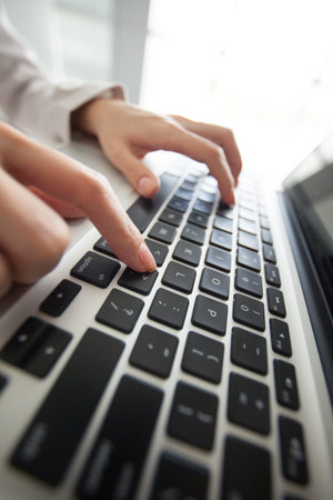 Female hand pressing laptop buttonの写真素材