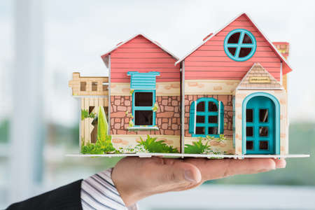 Close-up of a male hand holding a house miniatureの写真素材