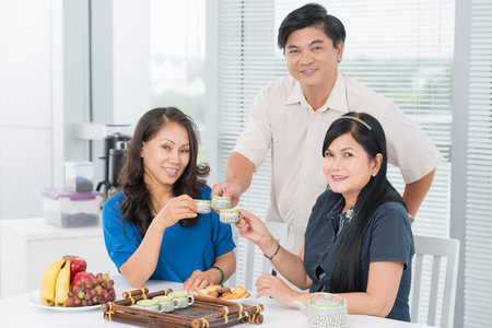 Portrait of charming seniors clinking cups of teaの写真素材
