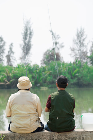 Rear view of two fishers waiting for fishの写真素材