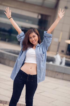 Vertical portrait of a happy youngster standing with hands up