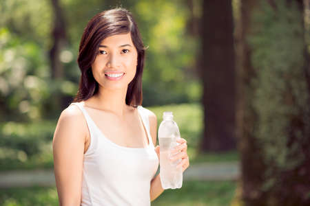Close-up portrait of a young sportswoman with a waterbottle in handsの写真素材
