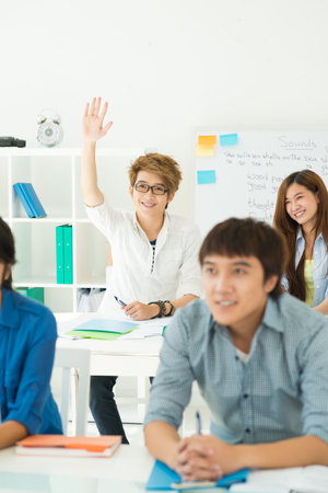Teen boy raising hand at English class