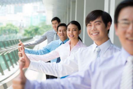 Portrait of a business team in success showing thumb-up on the foregroundの写真素材