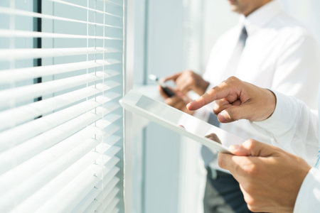 Close-up of businessman holding touchpad and pointing at its screenの写真素材