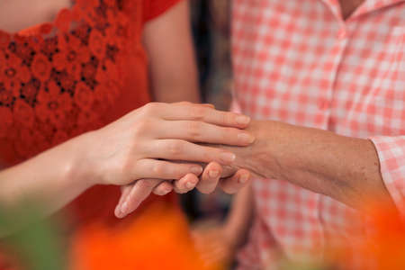 Close-up of a young woman touching a hand of an elderly one with careの写真素材