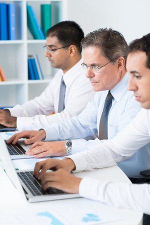 Row of smart businessmen networking in office