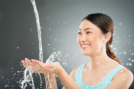 Isolated image of a woman smiling while water splashing in her hands