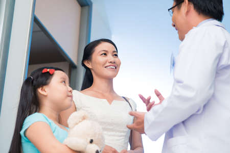 Image of a pediatrician talking with a mom of his little patient viewed belowの写真素材