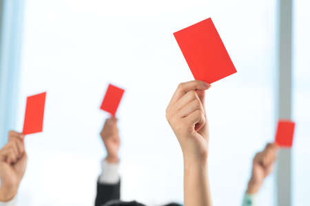 A group of people declined something showing red card on the foregroundの写真素材