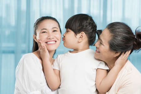 Copy-spaced image of a little girl kissing her mother while bonding her grandmother insideの写真素材