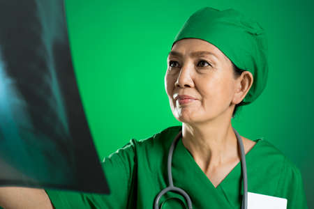 Close-up image of a senior female doctor analyzing an X-ray on the foregroundの写真素材