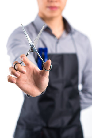Vertical image of a barber holding professional scissors in a hand on the foreground