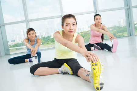  Young women doing stretching exercises in the aerobics class on the foreground の写真素材