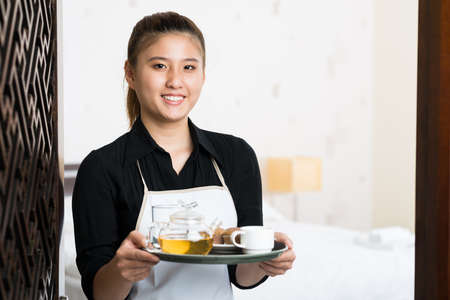 Copy-spaced portrait of a young waitress with prepared breakfast on the trayの写真素材