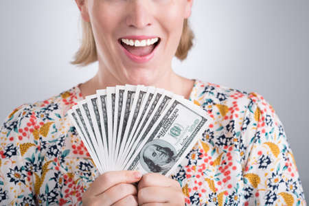 Cropped image of a woman holding dollars in hands on the foregroundの写真素材
