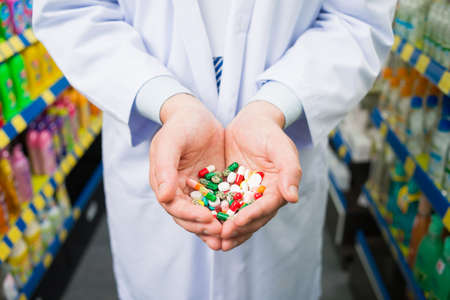 Cropped image of a pharmacist holding many colorful pills in the palms on the foregroundの写真素材