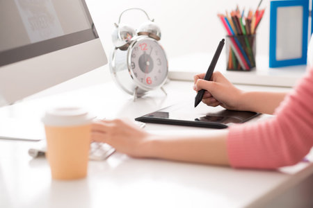 Cropped image of a graphic designer using digital tablet in his work on the foreground
