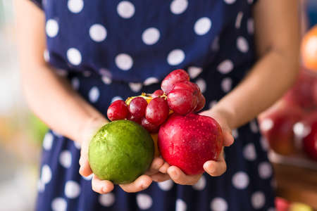Close-up human hands holding fresh fruits on the foregroundの写真素材
