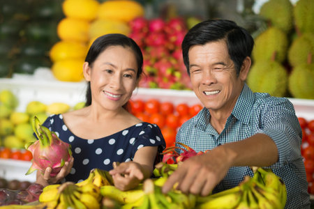 Close-up image of a senior couple buying fruits and vegetables in the market on the foreground